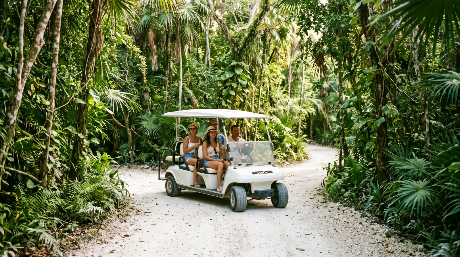 Carrito de golf blanco circulando por un camino de arena entre la selva de Tulum