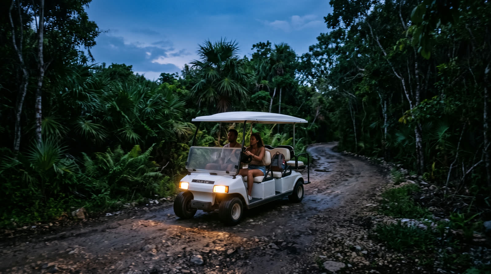 Carrito de golf circulando por un camino de la selva de Tulum al anochecer, con los faros encendidos